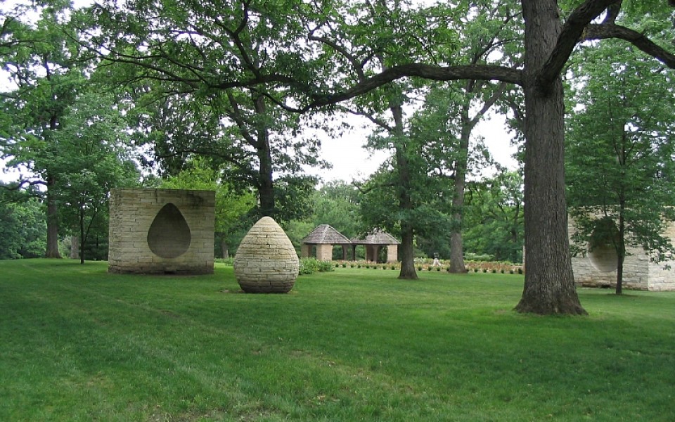 An egg-shaped stone sculpture stands before a block of stone with the shape of an egg cut out of it